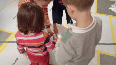 Kinder beim Kerzenziehen aus dem farbigen Wachstopf